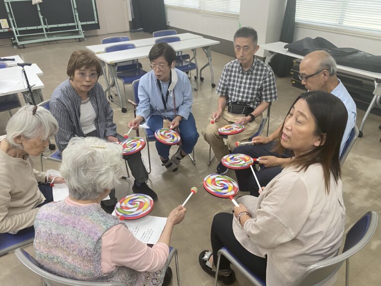 脳トレ音楽教室の会で、参加者がカラフルな打楽器を手に音楽に合わせる様子